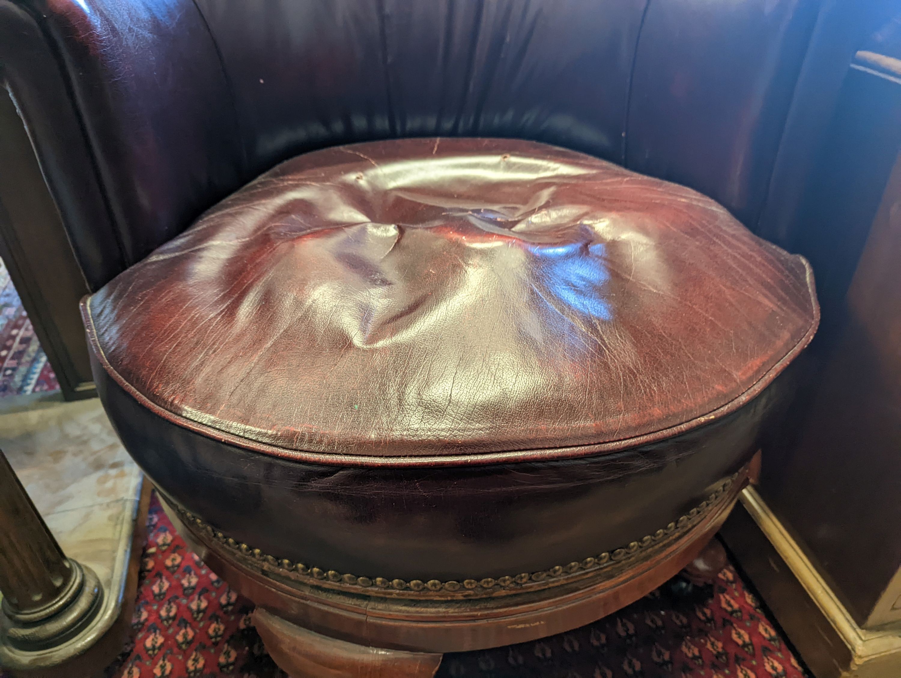 An early 20th century oak and burgundy leather tub framed swivel desk chair, width 70cm, depth 60cm, height 82cm